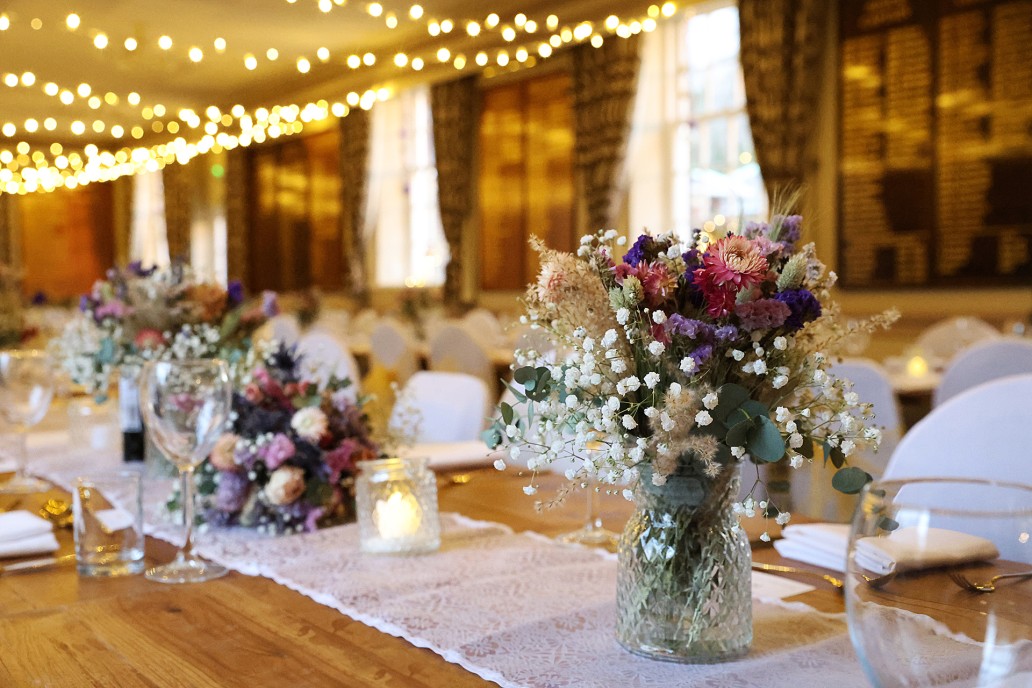 Vase of flowers on dining table, decorated for a wedding reception at Addington Palace Golf Club